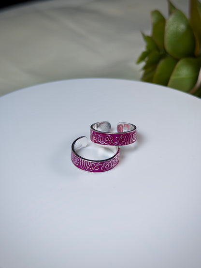 Silver toe rings with pink enamel on a white surface