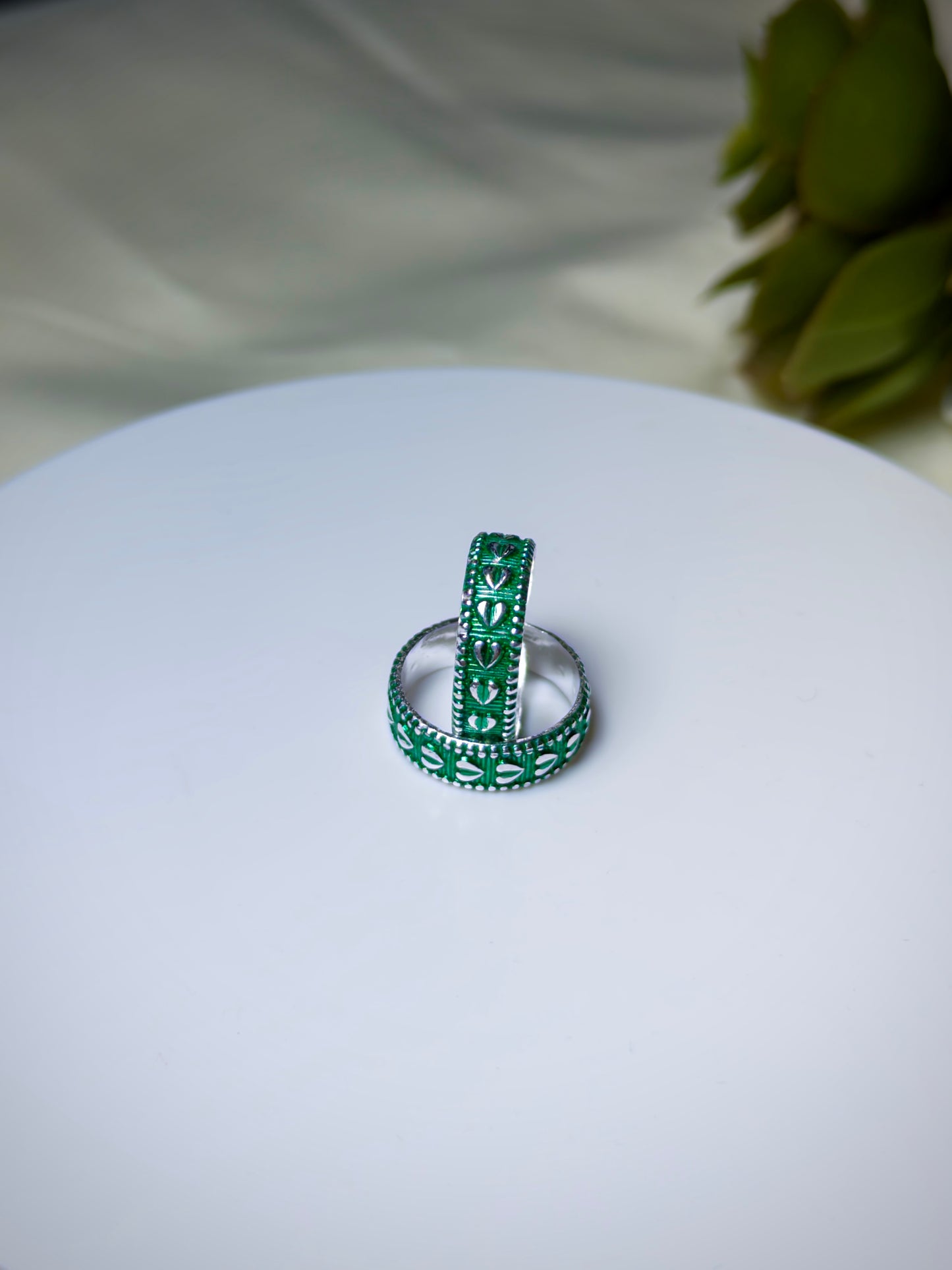 Green toe ring s on a white surface with a blurred green plant in the background