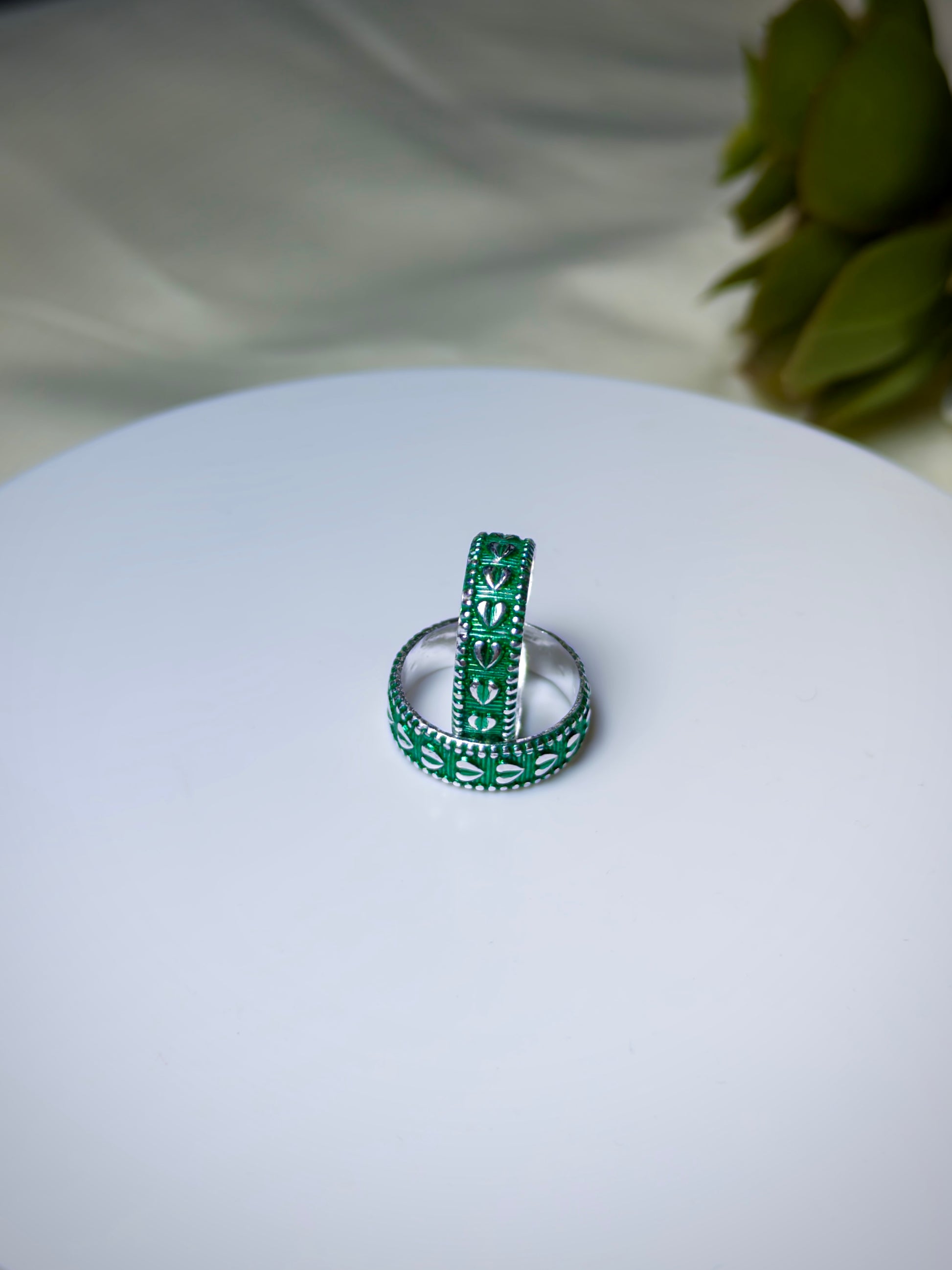Green toe ring s on a white surface with a blurred green plant in the background