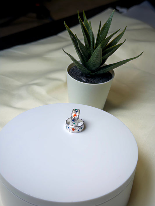 Two silver toe rings on a white surface with a potted plant in the background