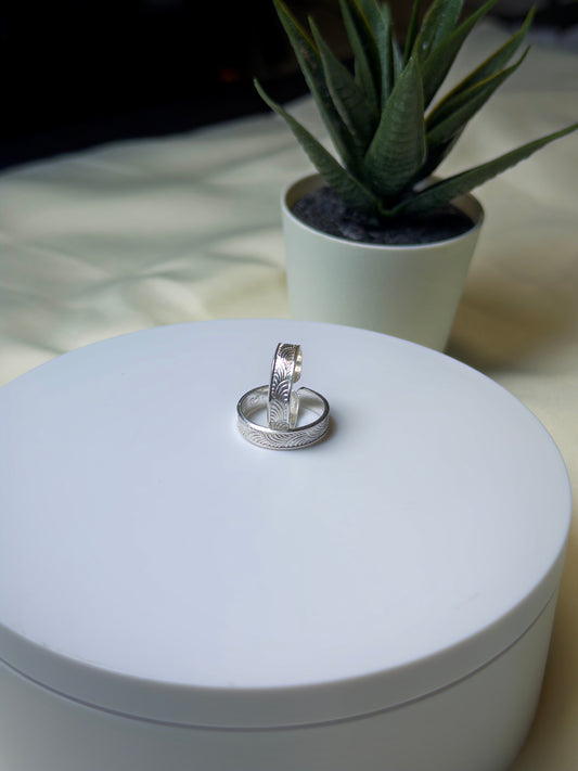Silver toe ring on a white cylindrical object with a plant in the background