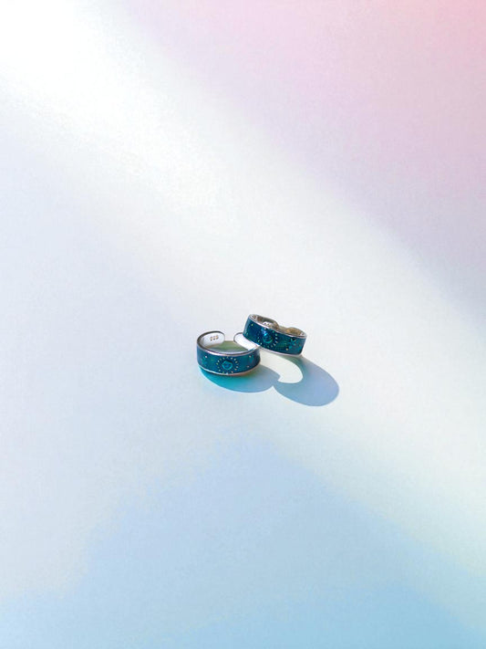 Two sea green toe rings on a gradient background