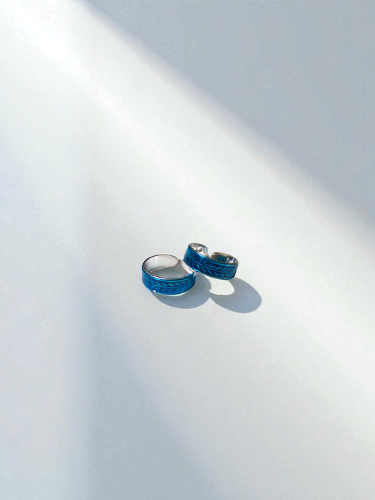 Two blue toe rings on a white surface with a soft shadow